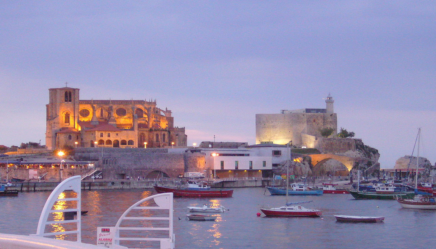 Le crépuscule dans ce port de Cantabrique: l'église Santa Maria de la Asunción illuminée, et à droite le château.